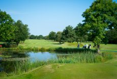 Lake view with golfers walking 16th High